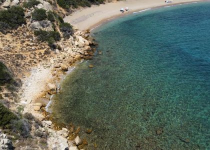 Aerial shot of a serene beach cove with clear turquoise waters and rocky shoreline.